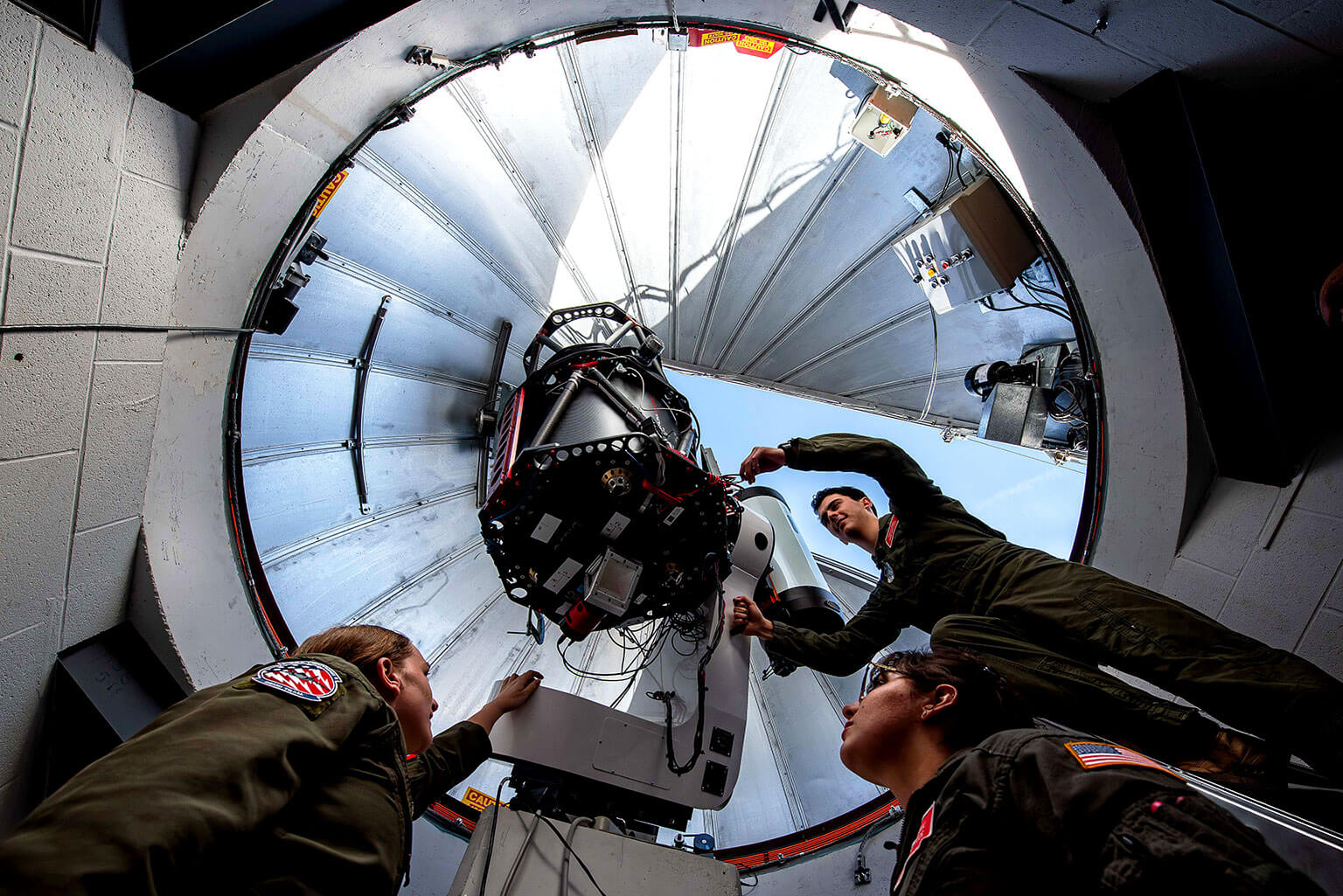 Cadet 2nd Class Brianna McVay, left, and Cadet 3rd Class Bethany Firooz watch as Cadet 3rd Class Ryan Kovacs makes minor modifications to the 0.5-meter Falcon telescope in the U.S. Air Force Academy Observatory.