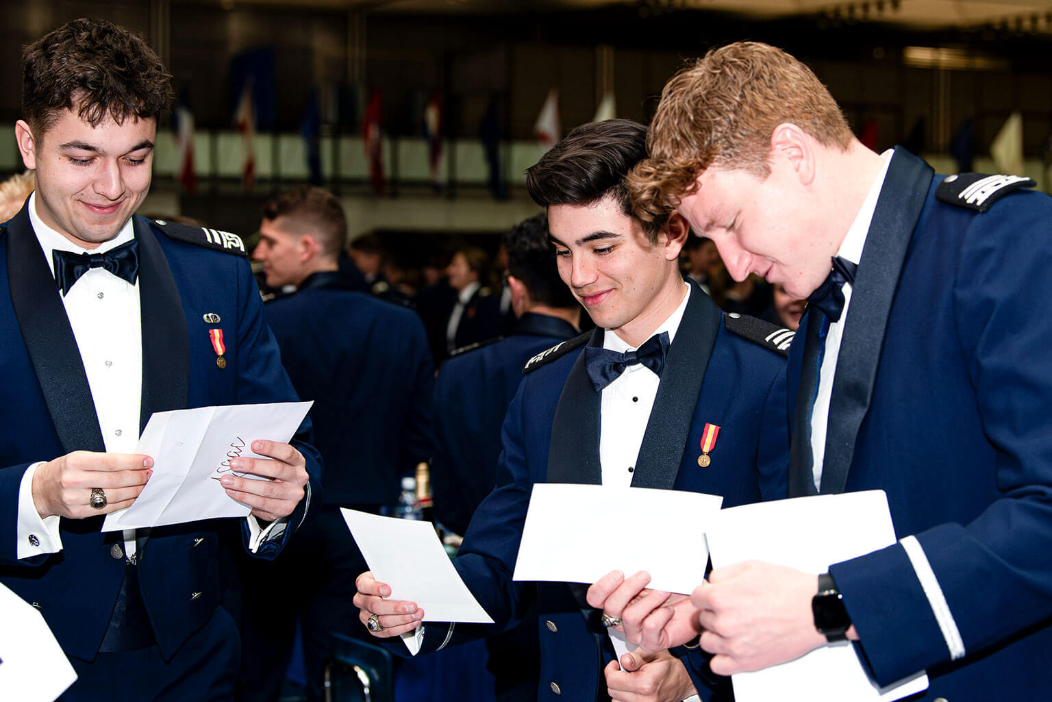 Cadets 1st Class Isaac Stewart, left, Noah Lewis and Blaze Williams receive notifications of their base assignments on 100s Night in Mitchell Hall.