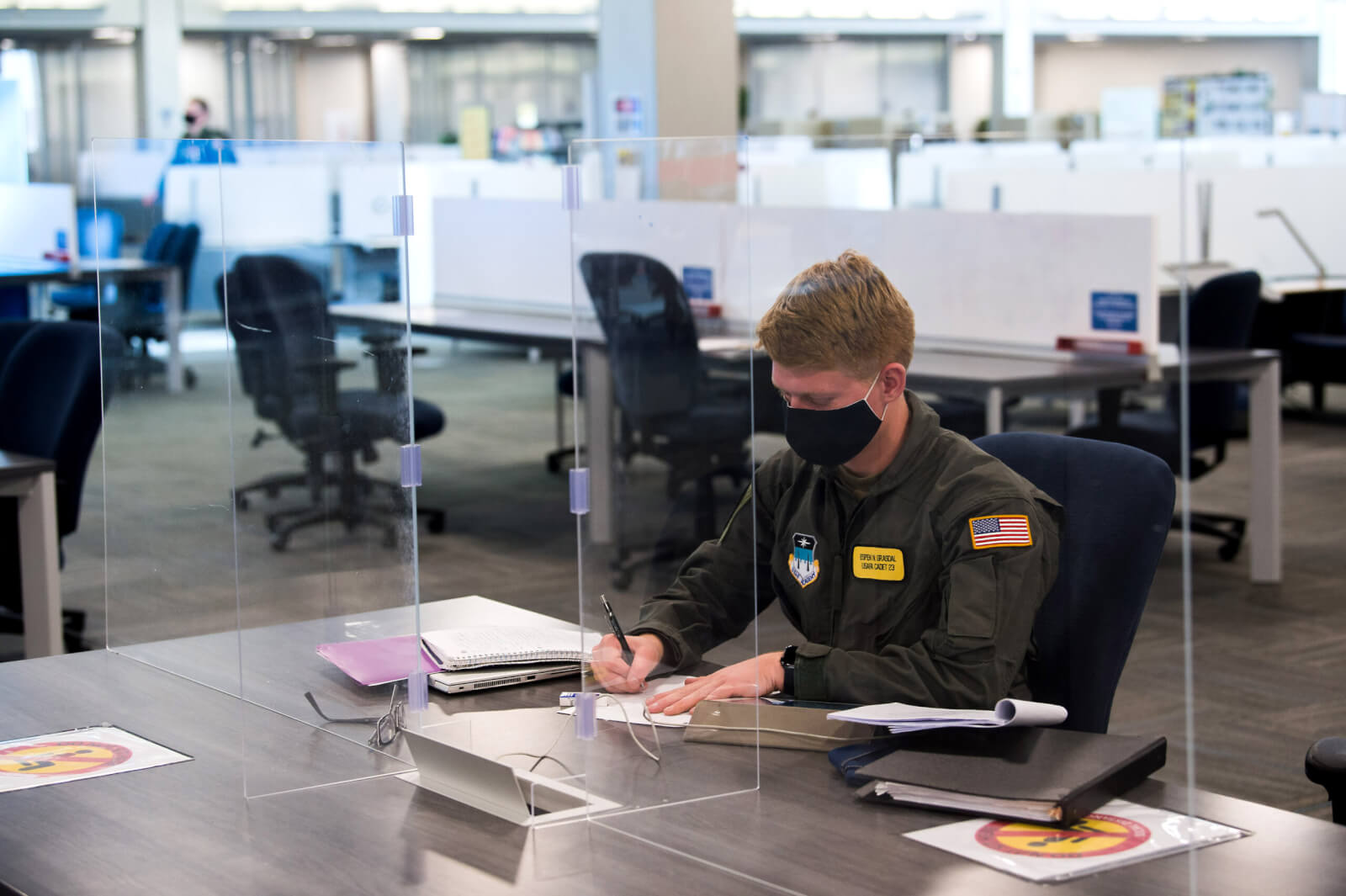 Cadet wearing mask working behind plexiglass