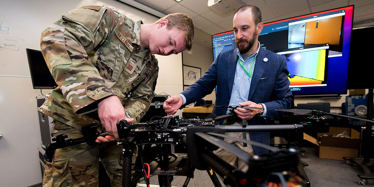 Cadet working on a drone with help from an instructor.