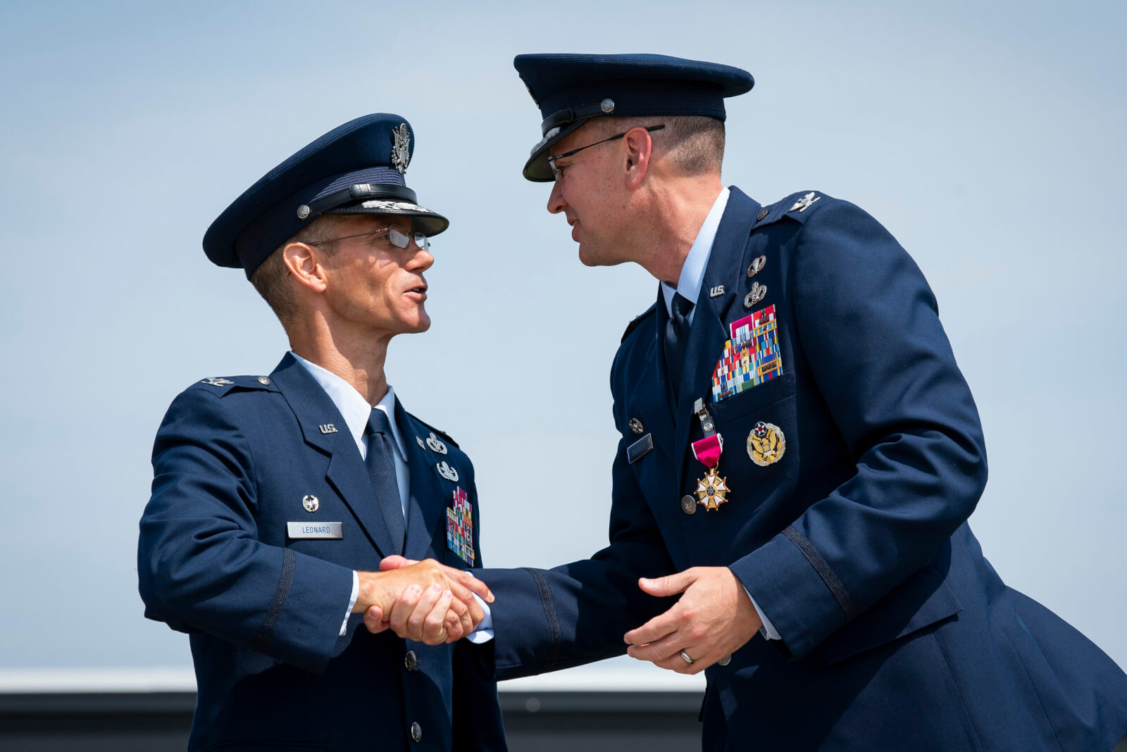 Col. Christopher Leonard, commander of the 10th Air Base Wing, shakes hands with his predecessor, Col. Brian Hartless, June 18, 2021
