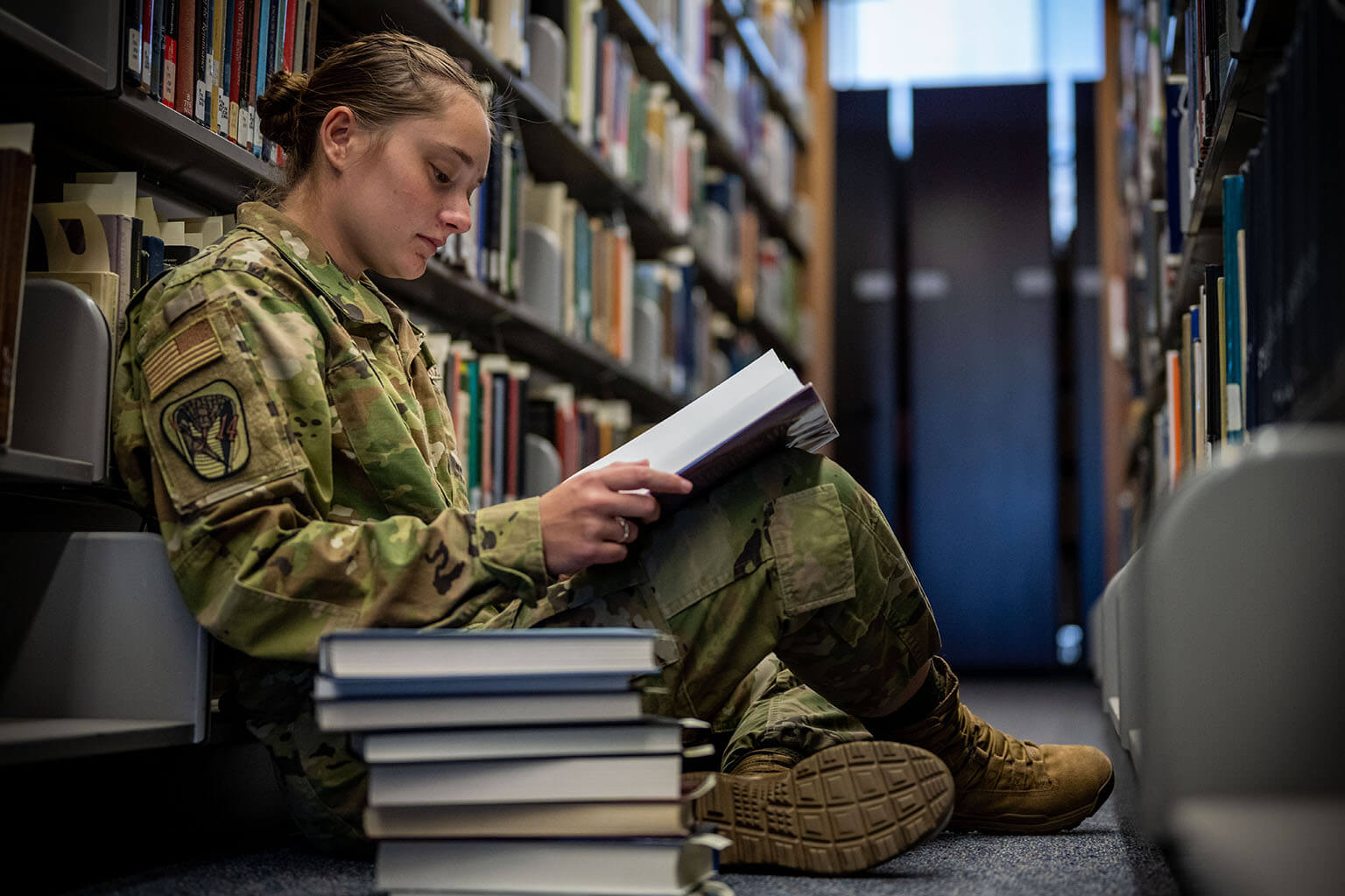 Female cadet reading books in library