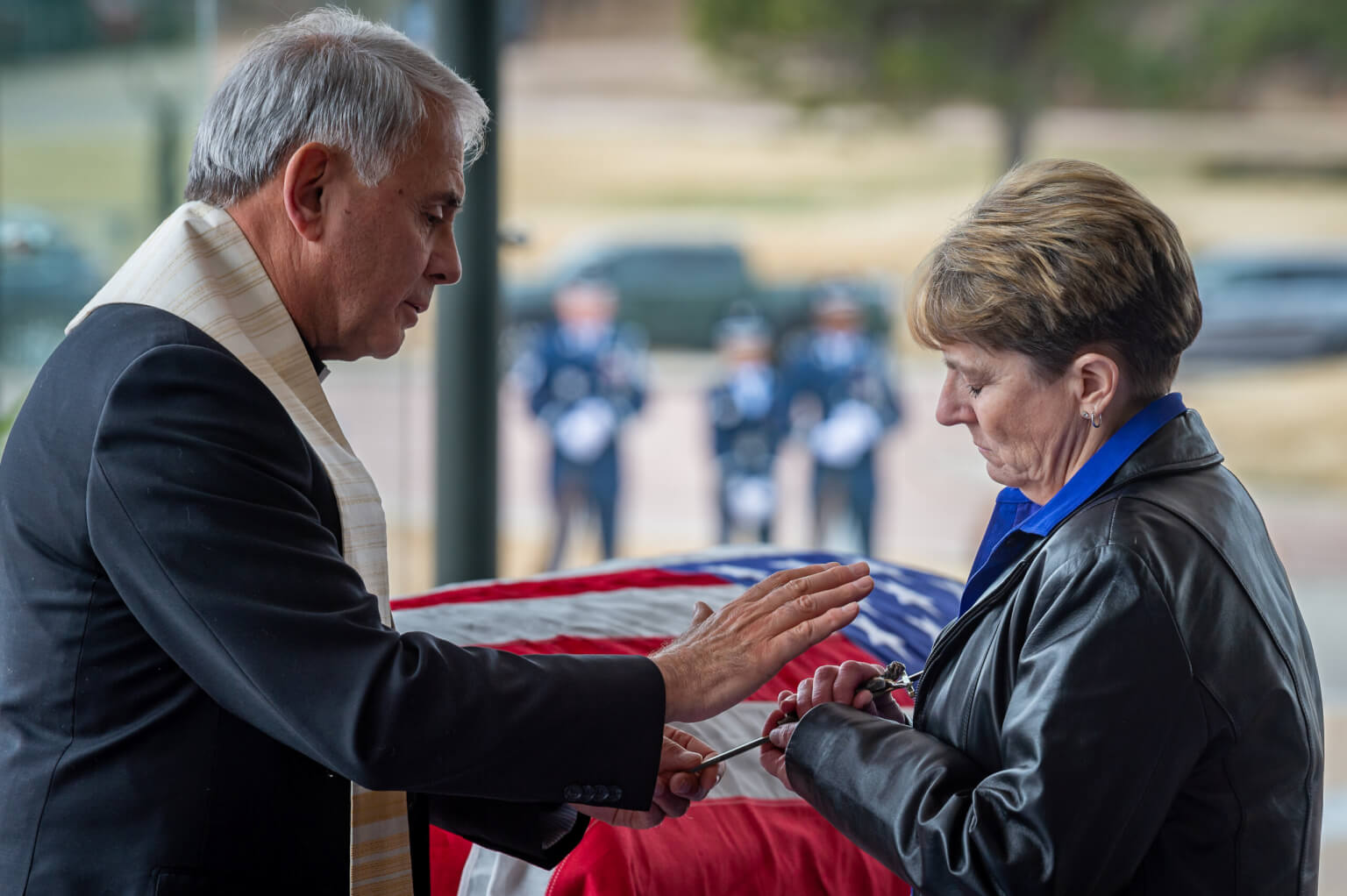 Father Robert Bruno, a retired colonel and former U.S. Air Force Academy command chaplain, blesses a cross held by Kay Scott, daughter of Lt. Gen. Winfield W. “Skip” Scott Jr.