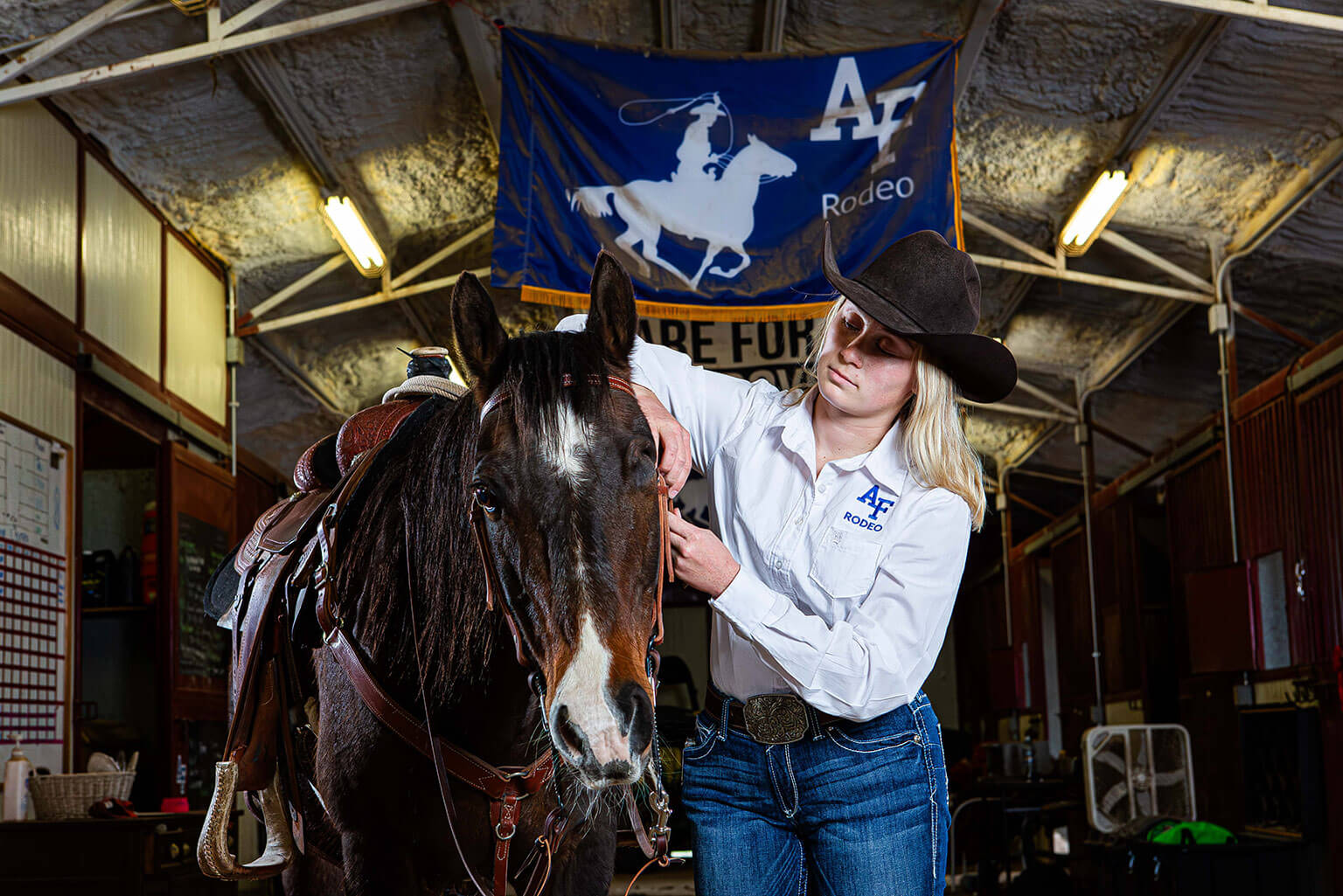 Cadet 2nd Class Colette McClanahan saddles her horse, Bear, in the U.S. Air Force Academy Rodeo Club barn.