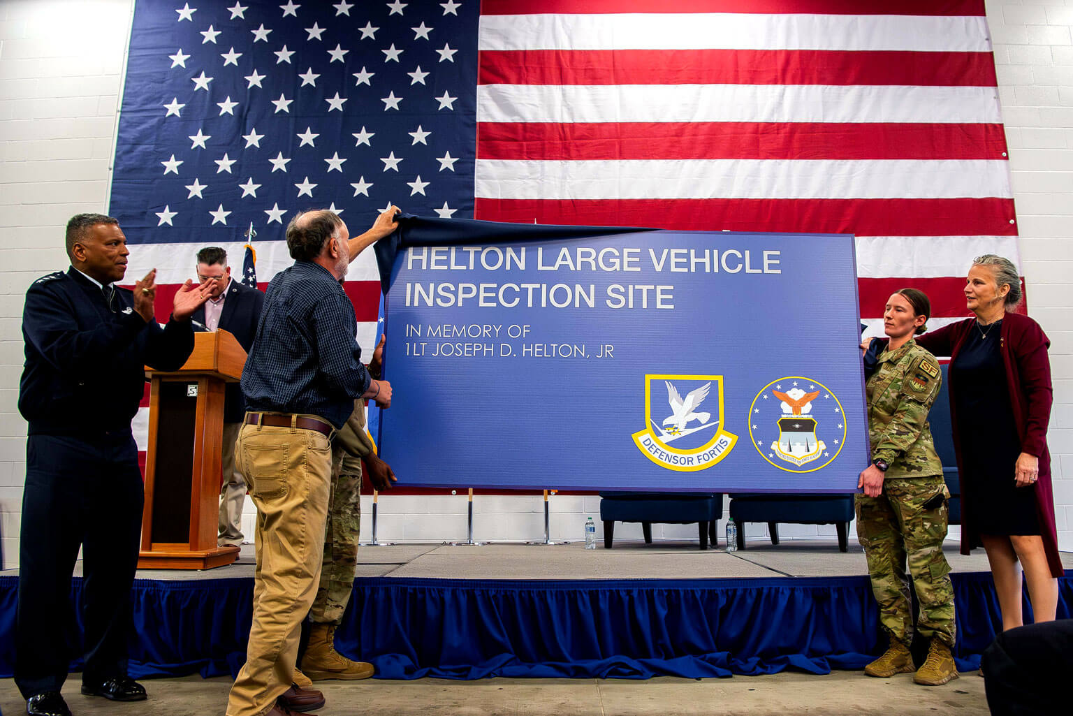 U.S. Air Force Academy Superintendent Lt. Gen. Richard Clark applauds as 1st Lt. Joseph D. Helton Jr.’s mother, Jiffy Helton-Sarver, watches his father, Joseph Helton, and Senior Airman Chelsea McComb unveil the new sign for the Large Vehicle Inspection Site.
