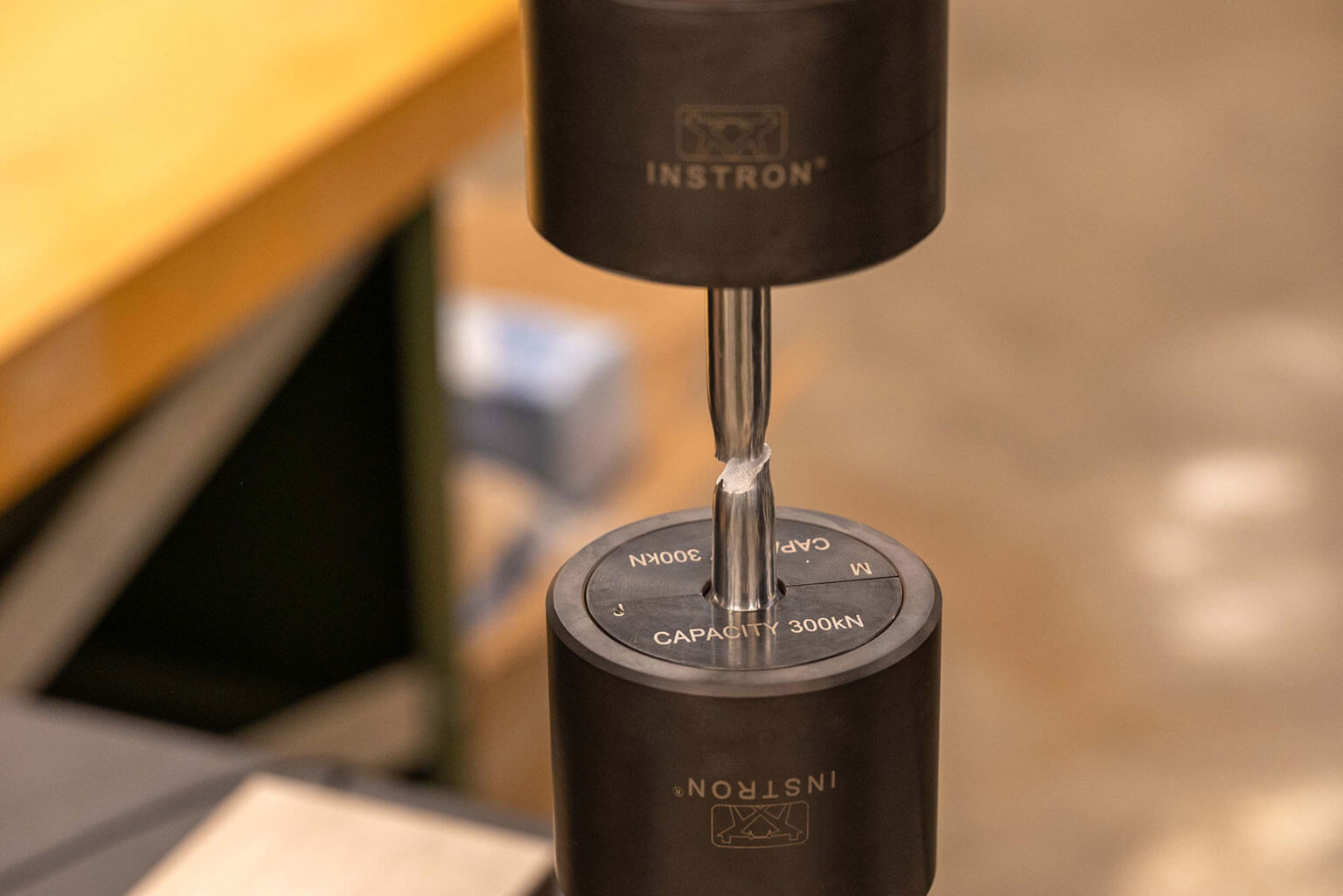 A piece of metal alloy shears under stress during a tensile test at the Mechanical Engineering Department, U.S. Air Force Academy, Colo., March 18, 2026. Cadets use a hydraulic machine to pull apart alloy material to determine if the material is an appropriate choice for a specific design. (U.S. Air Force photo by Tech. Sgt. Zach Vaughn)