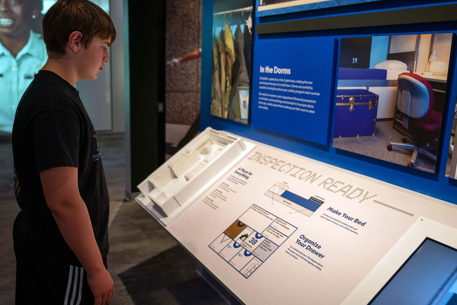 David Goddard, a 13-year-old resident of Colorado Springs and grand opening attendee, views the layout of a cadet dorm room during the Hosmer Visitor Center grand opening at the U.S. Air Force Academy, Colo., May 16, 2026. Interactive exhibits throughout the center give visitors a closer look at cadet life, military training and the traditions that shape the Academy experience. (U.S. Air Force photo by Tech. Sgt. Zach Vaughn)