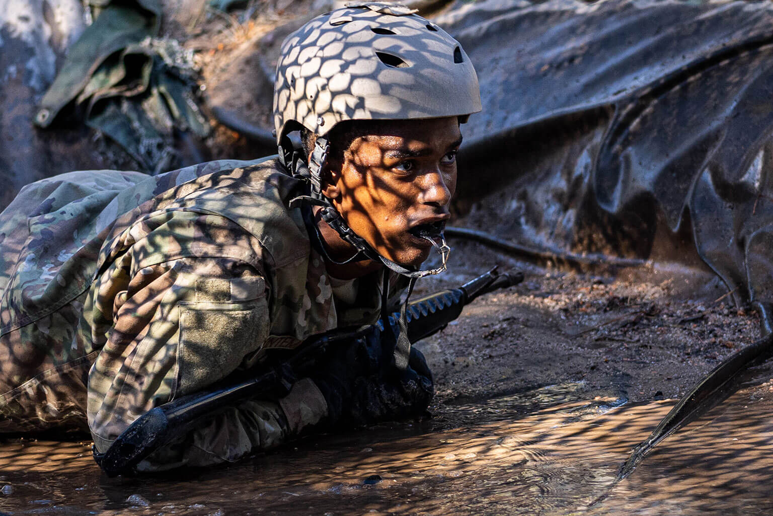 A basic cadet low crawls through an obstacle at the Jacks Valley Assault Course during Basic Cadet Training at the U.S. Air Force Academy, Colo., July 26, 2026. Jacks Valley is the Academy’s primary field location for warfighting and leadership training events such as the Basic Cadet Training program. (U.S. Air Force photo by Jonathan Suni)