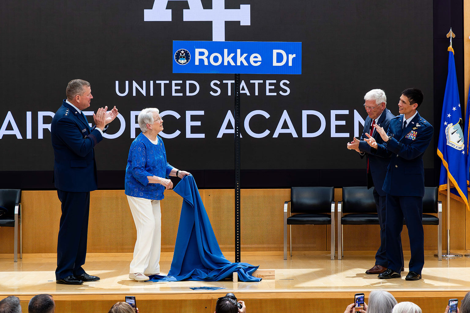 Pam Rokke (middle-left), wife of retired Lt. Gen. Ervin J. Rokke, unveils the Rokke Drive street sign during a ceremony at Polaris Hall, U.S. Air Force Academy, Colo., July 24, 2026. Retired Lt. Gen. Rokke, Class of 1962, was the first Academy graduate to serve as Dean of the Faculty. Academy officials honored his service by naming a cadet area road “Rokke Drive.” (U.S. Air Force photo by Trevor Cokley)