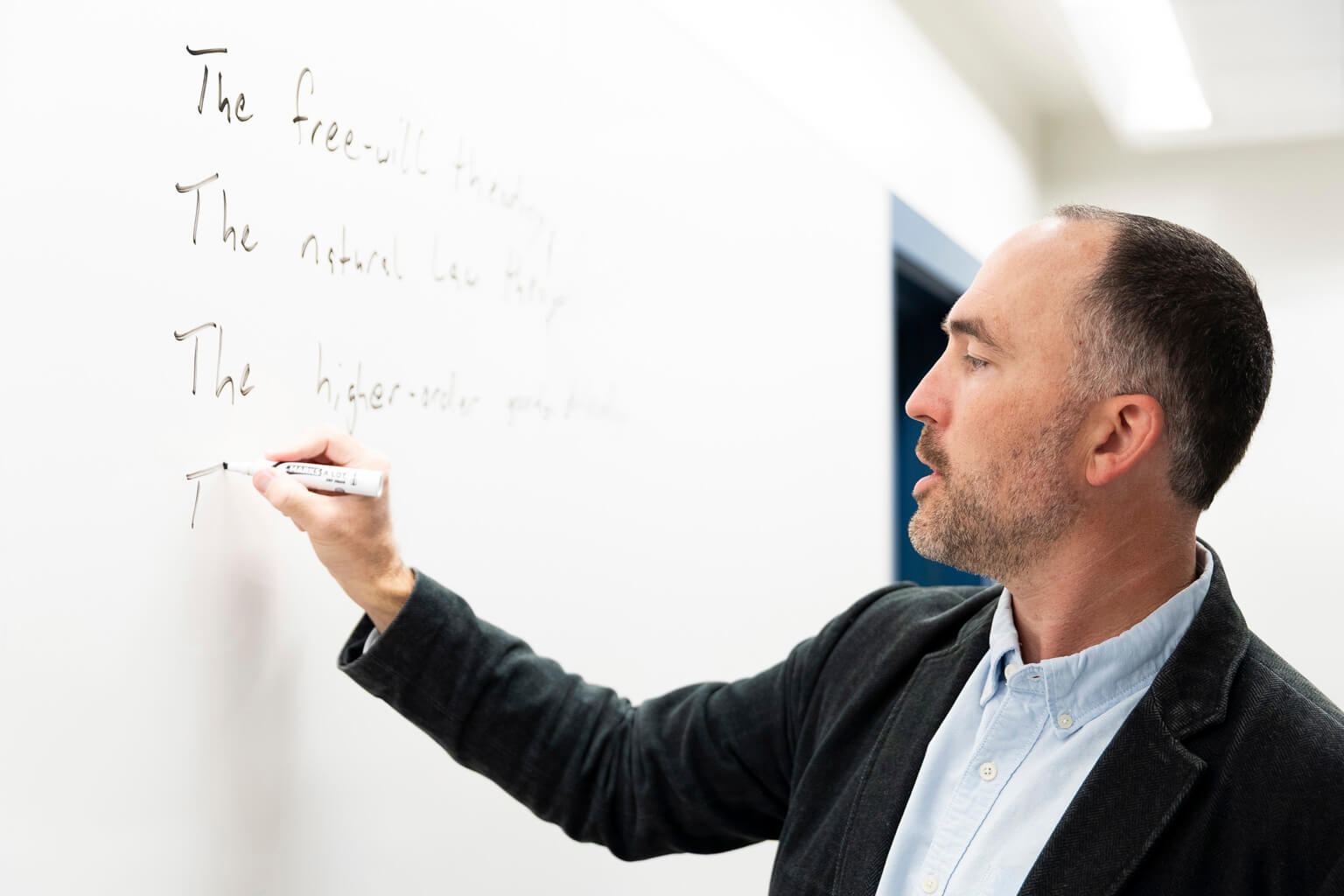 Adam Pelser, a professor of philosophy at the U.S. Air Force Academy, writes on a whiteboard during a C.S. Lewis and Philosophy class in Colorado Springs, Colorado, Oct. 22, 2026. The course examines philosophical arguments and themes through the writings of C.S. Lewis, offering cadets opportunities to explore subjects beyond their primary fields of study. (U.S. Air Force photo by Ray Bahner)