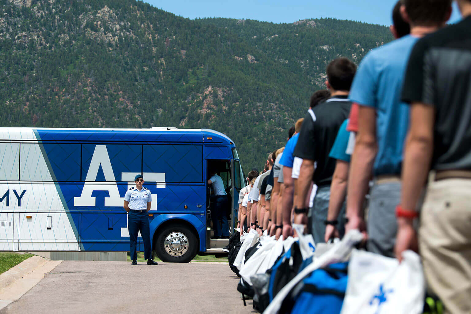U.S. Air Force Academy appointees waiting in line to board a bus. A member of the cadet cadre stands in the distance in front a an Academy bus. U.S. Air Force Academy appointees waiting in line to board a bus. A member of the cadet cadre stands in the distance in front a an Academy bus.