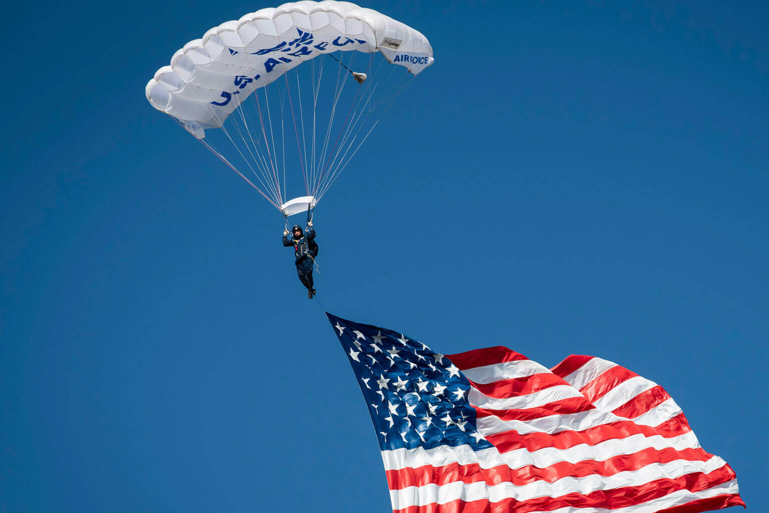 A Wings of Blue cadet parachuting with an American flag during Parents' Weekend festivities. A Wings of Blue cadet parachuting with an American flag during Parents' Weekend festivities.