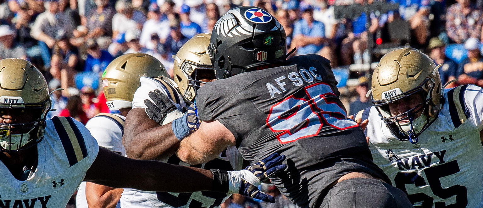 U.S. Air Force Academy and Navy football players engage in a spirited game on the field, showcasing athleticism and teamwork.