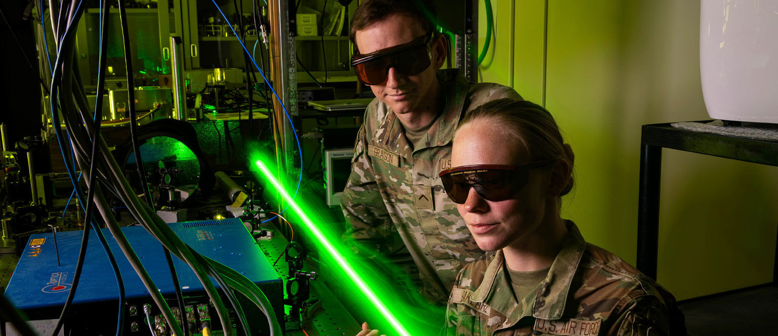 Two cadets running an experiment using a laser.
