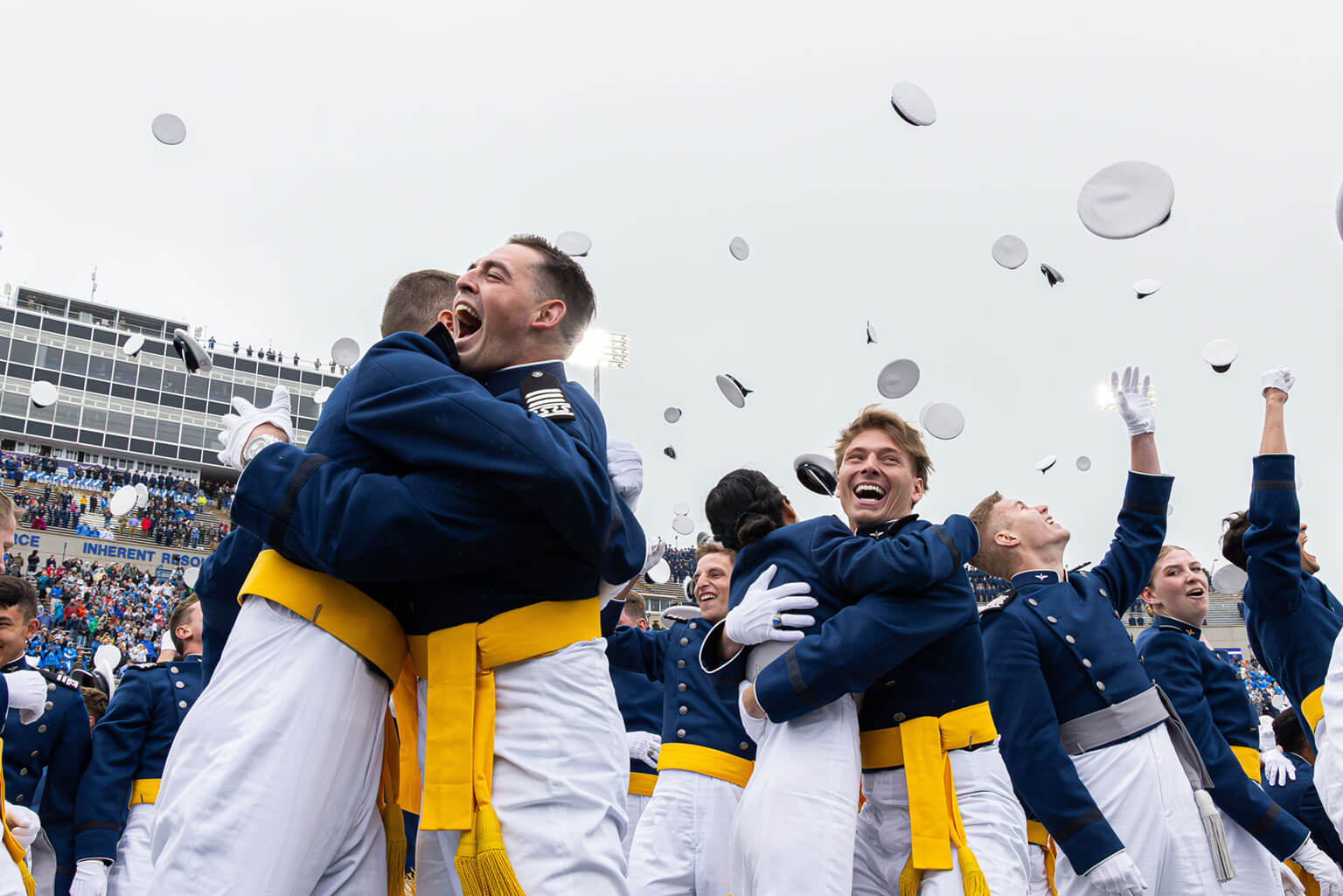 U.S. Air Force Academy Class of 2025 graduates toss their hats skyward in Falcon Stadium.