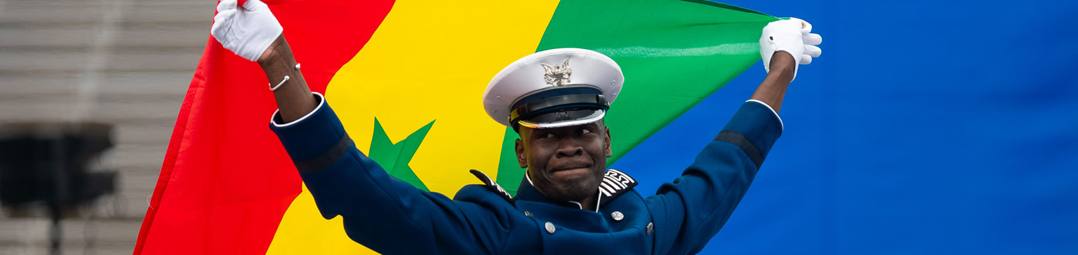 An international cadet proudly holds the Senegalese flag. The vibrant colors convey a sense of pride and celebration.