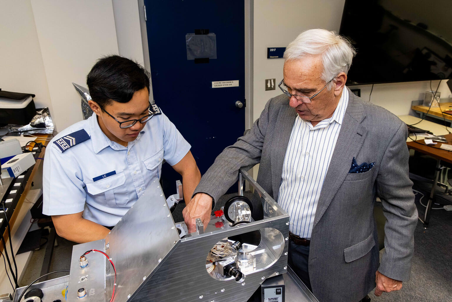 Cadet 2nd Class Alexander Le and Dr. Matthew McHarg examine the optics on the engineering unit of Falcon Optical Defense and Intelligence through Neuromorphics, Space Physics and Atmospheric Research Center.