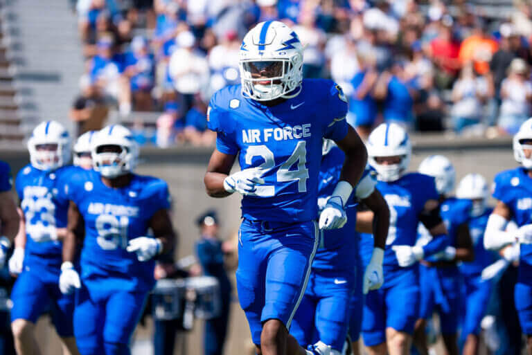 Air Force Falcons football players running on to Falcon Stadium field.