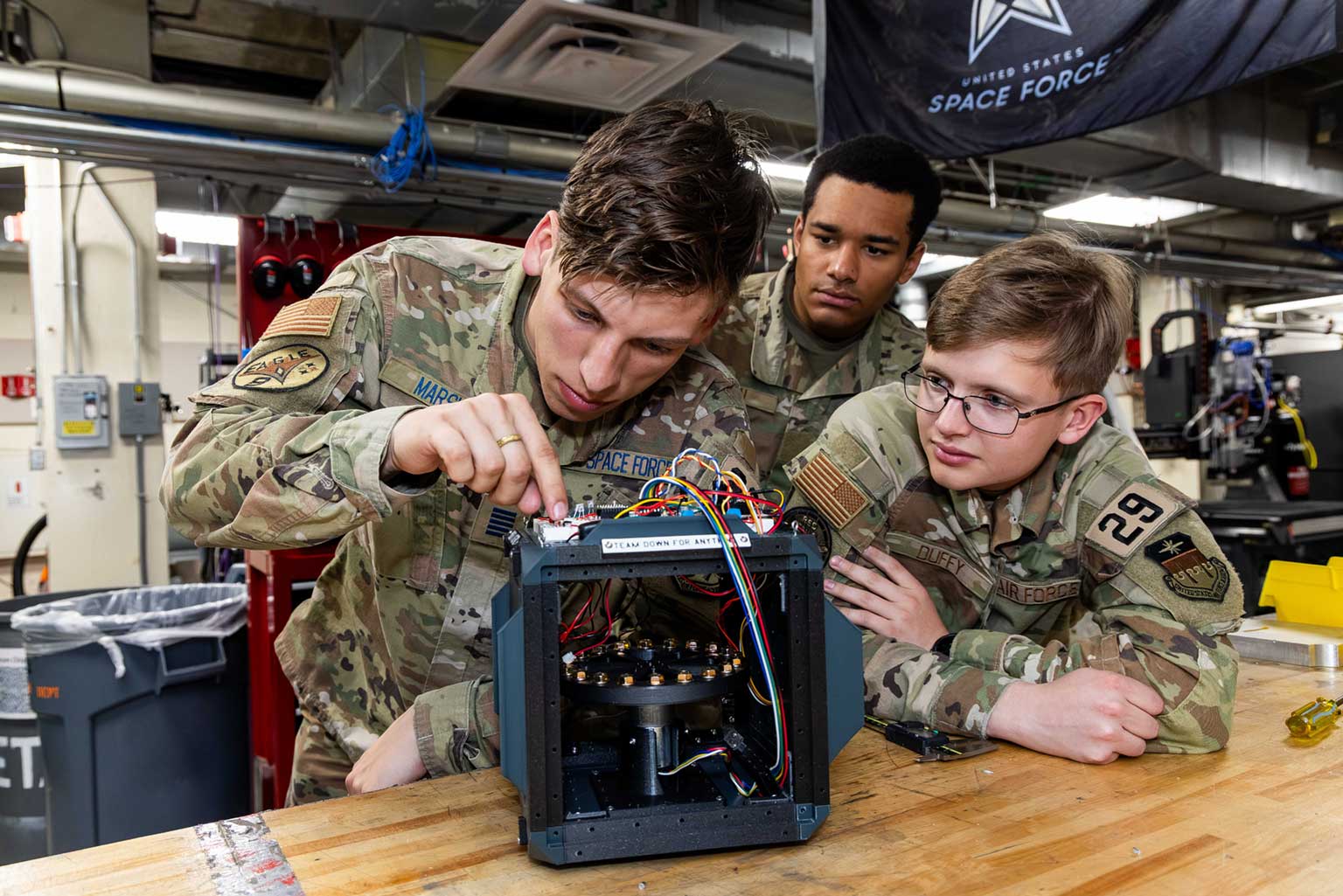 U.S. Air Force Academy cadets work together on a small device, highlighting their practical skills and teamwork in action.