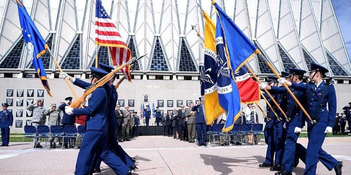 Cadet Honor Guard marching with flags in front of chapel