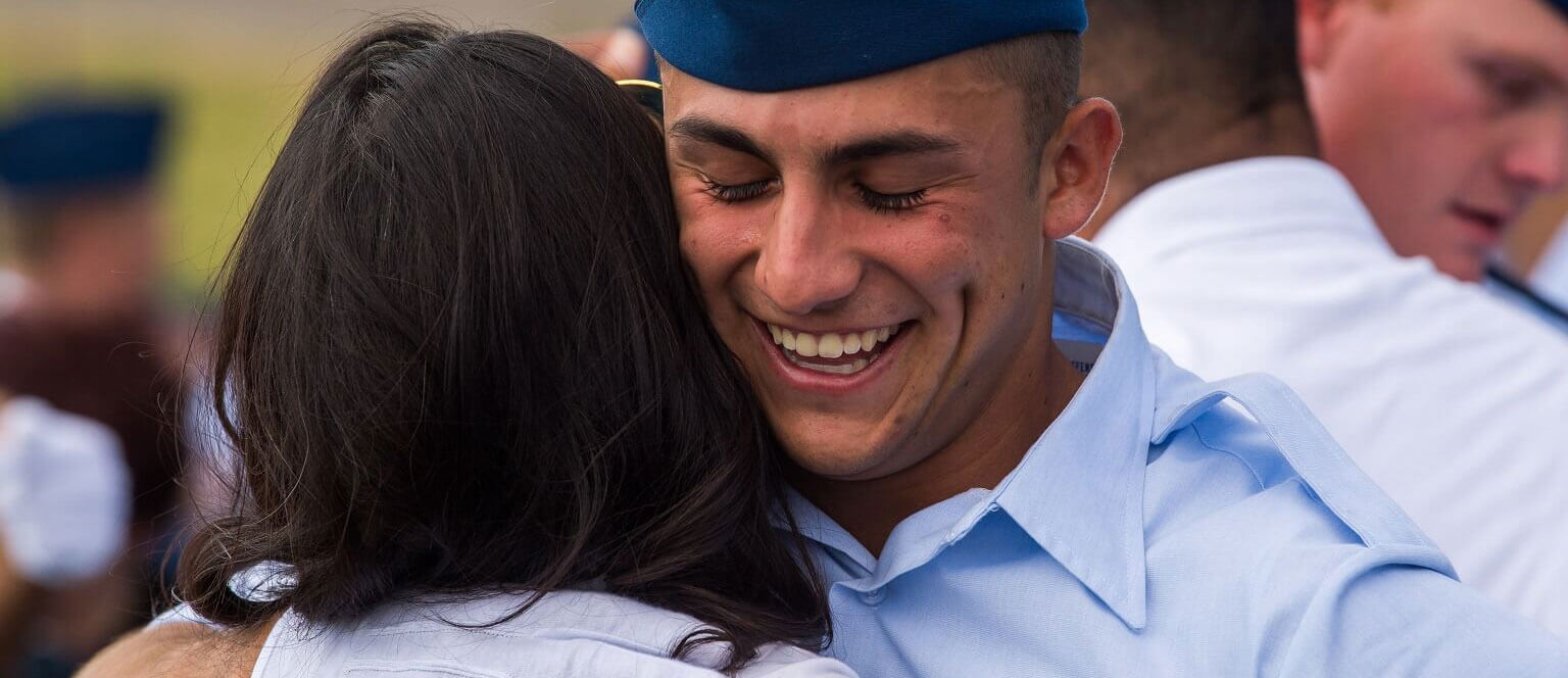 Male cadet hugging his sponsor family.