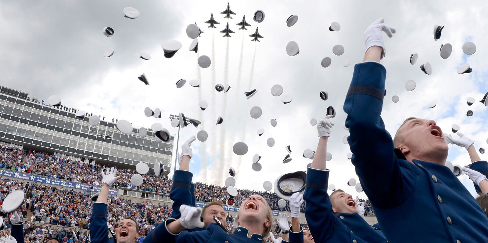 cadets throwing hats in air at graduation