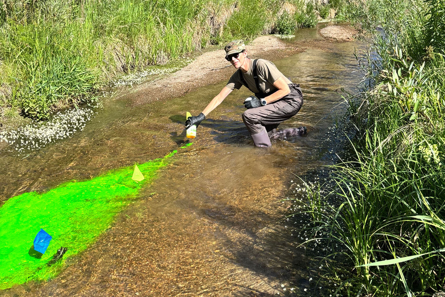 Lt. Col. Kathleen Smits, U.S. Air Force Reserve professor assigned to the U.S. Air Force Academy, releases fluorescent tracer dye into a stream during a CivEngr 351 Civil Engineering Practices exercise at the U.S. Air Force Academy, June 16, 2026. As part of water resources field operations, cadets track how the dye moves and disperses through the waterway to investigate the transport processes engineers use to understand contaminant movement, evaluate water quality and assess the behavior of natural water systems. (Courtesy photo by Cadet 2nd Class Abby Kuzio)