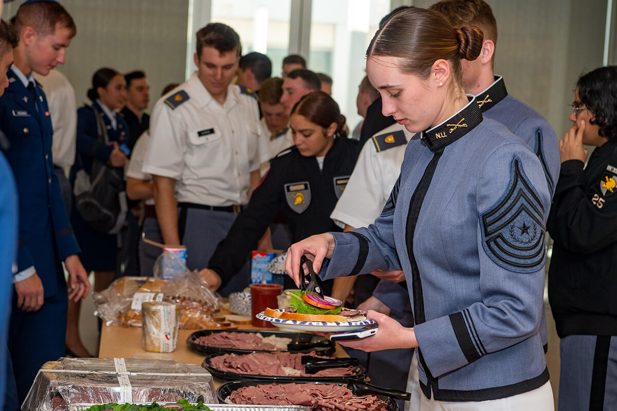Midshipmen and cadets at a buffet line 