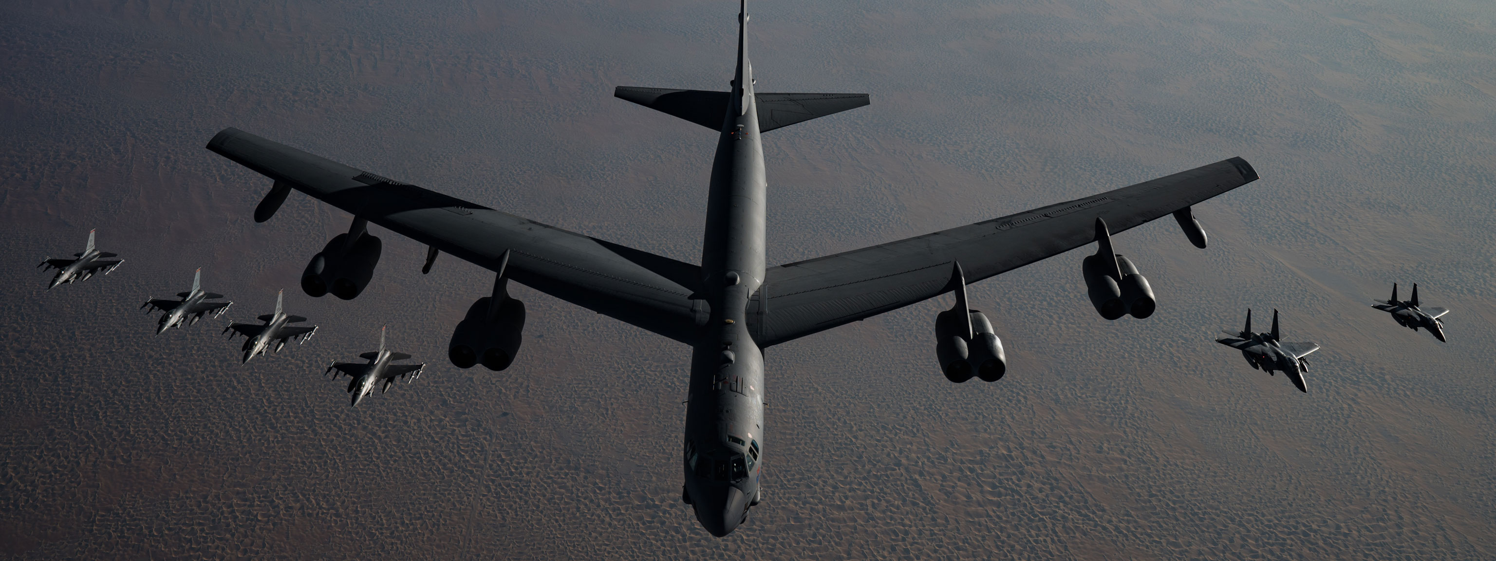 A B-52 bomber leads a formation of two F-15s and four F-16s flying in a tight military jet formation.