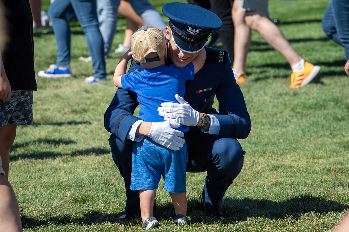 fourth class cadet hugs a small child at Stillman Parade Field.