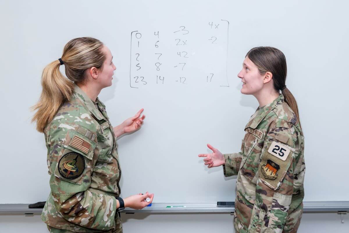 Two cadets discussing a math problem on a whiteboard. Undergraduate Women in Mathematics