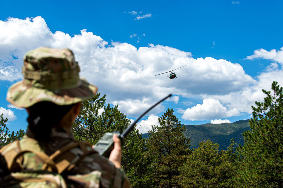 A member of combat survival training leadership communicates with a helicopter