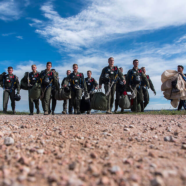 Skydiving cadets carrying gear.