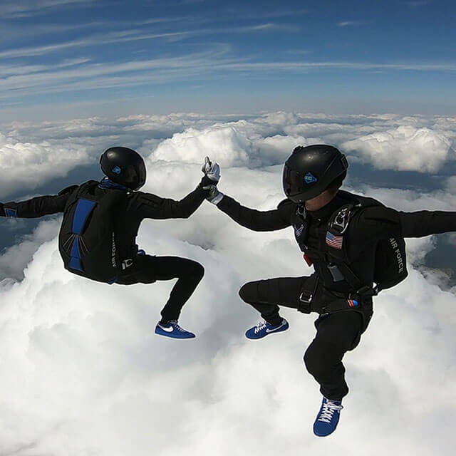 Two competition team members grasping hands in skydive