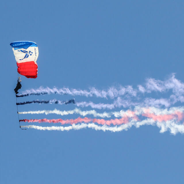 Wings of Blue member trailing colored smoke