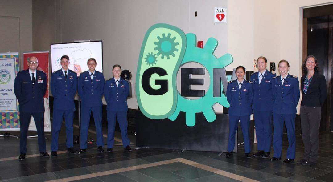 Cadets in front of the Genetically Engineered Machine Competition logo