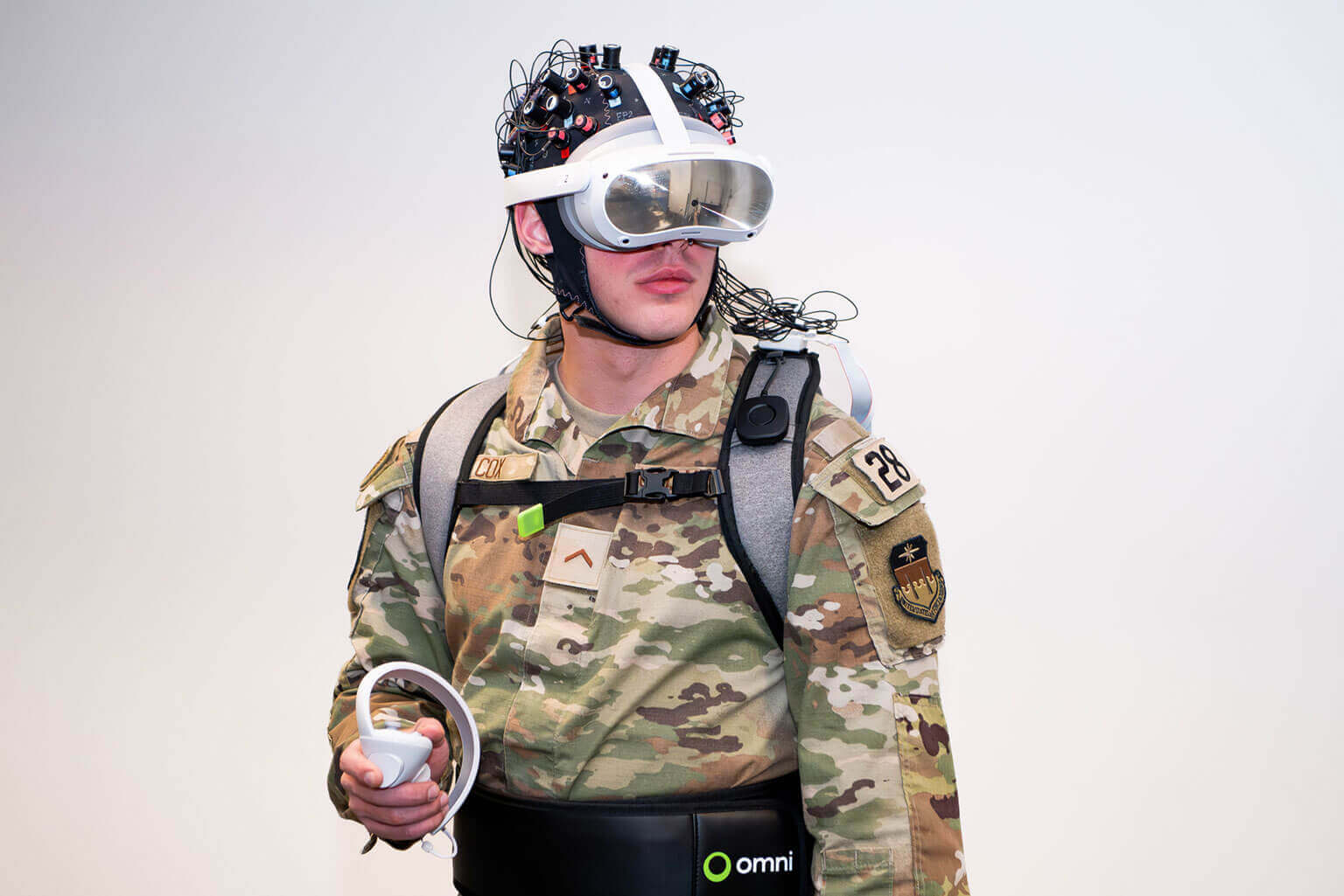 A cadet in a helmet holds a remote control, focused and ready for action in a military setting.
