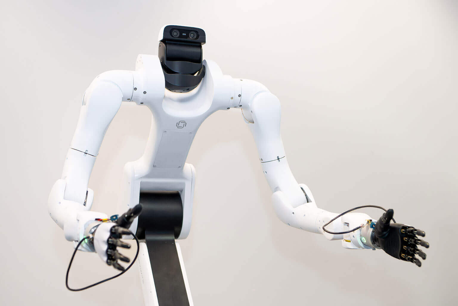 A white, humanoid robot with cameras for eyes and articulated arms extends its hands forward. The setting is minimalistic, conveying a futuristic tone.
