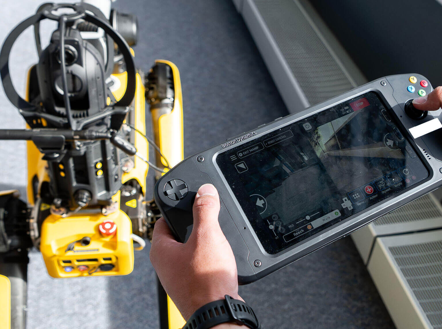 A cadet operates a tablet to remotely control a robot in a tactical environment.